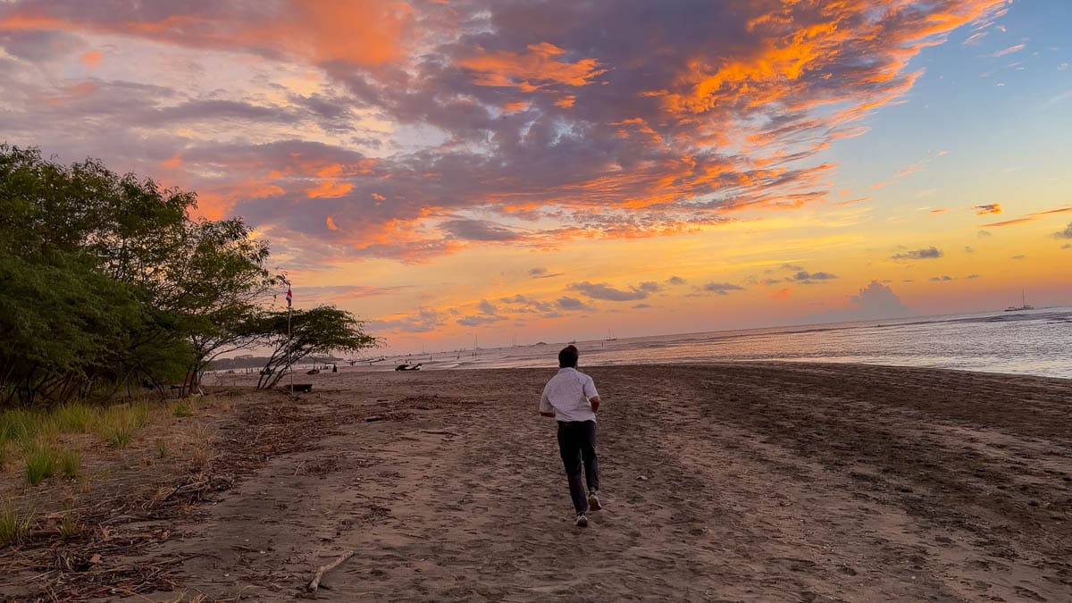 Riz running on Tamarindo Beach towards a dramatic sunset.
