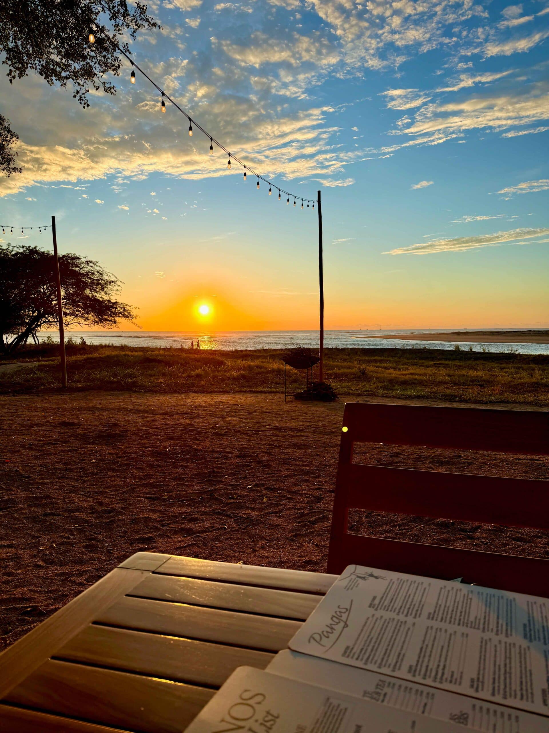 A shot of the fading yellow sun in the the horizon taken from a table at Pangas Restaurant. The menu is visible on the table.
