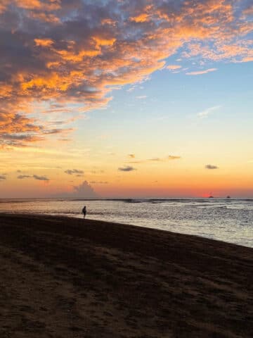 A shot of a man standing alone on Playa Tamarindo with a dramatic sunset behind him.