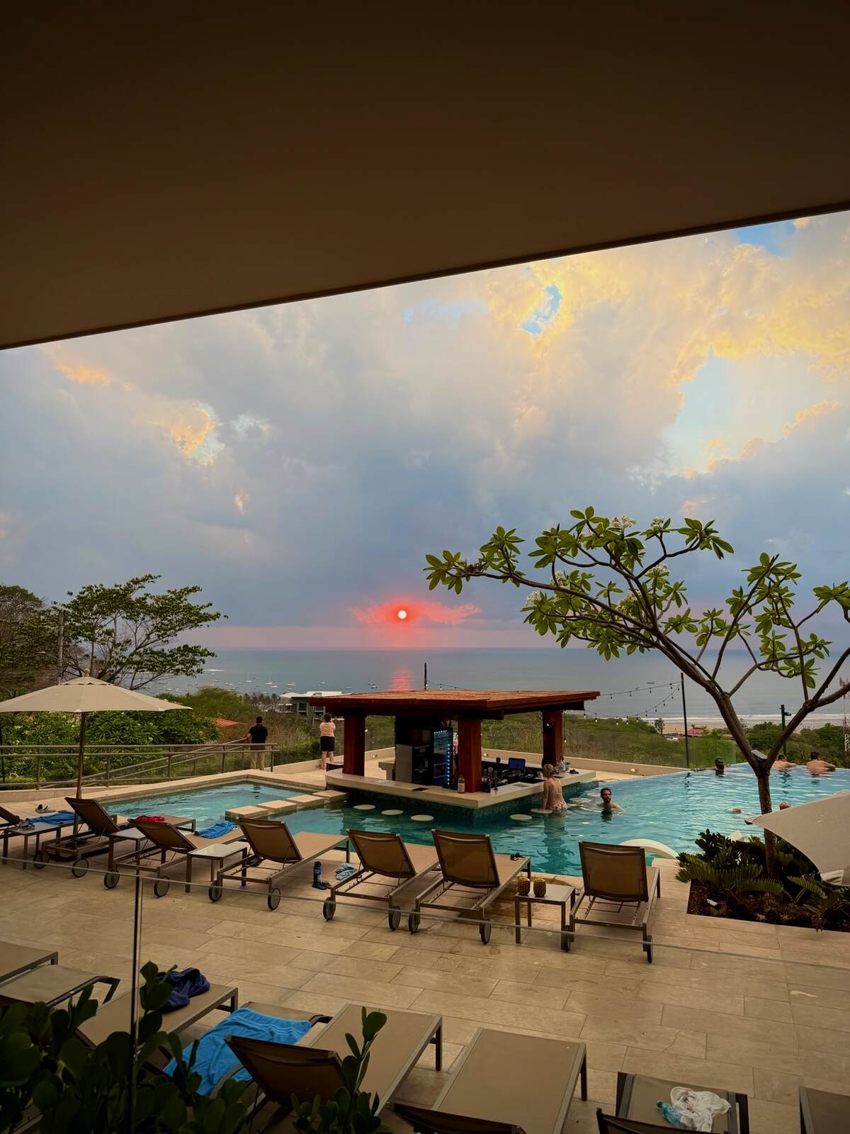 A view of the pool and wet bar at Wyndham Tamarindo during sunset.