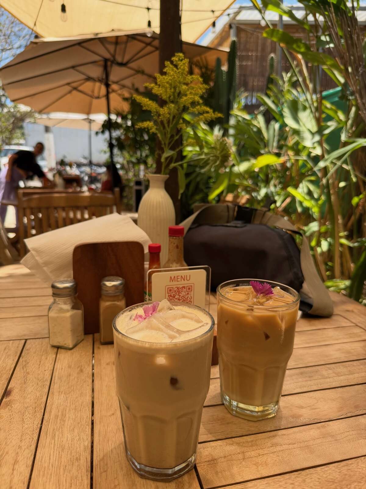 Two iced coffees on a table at Sol Bakery & Cafe in Tamarindo. Greenery can be seen in the background.