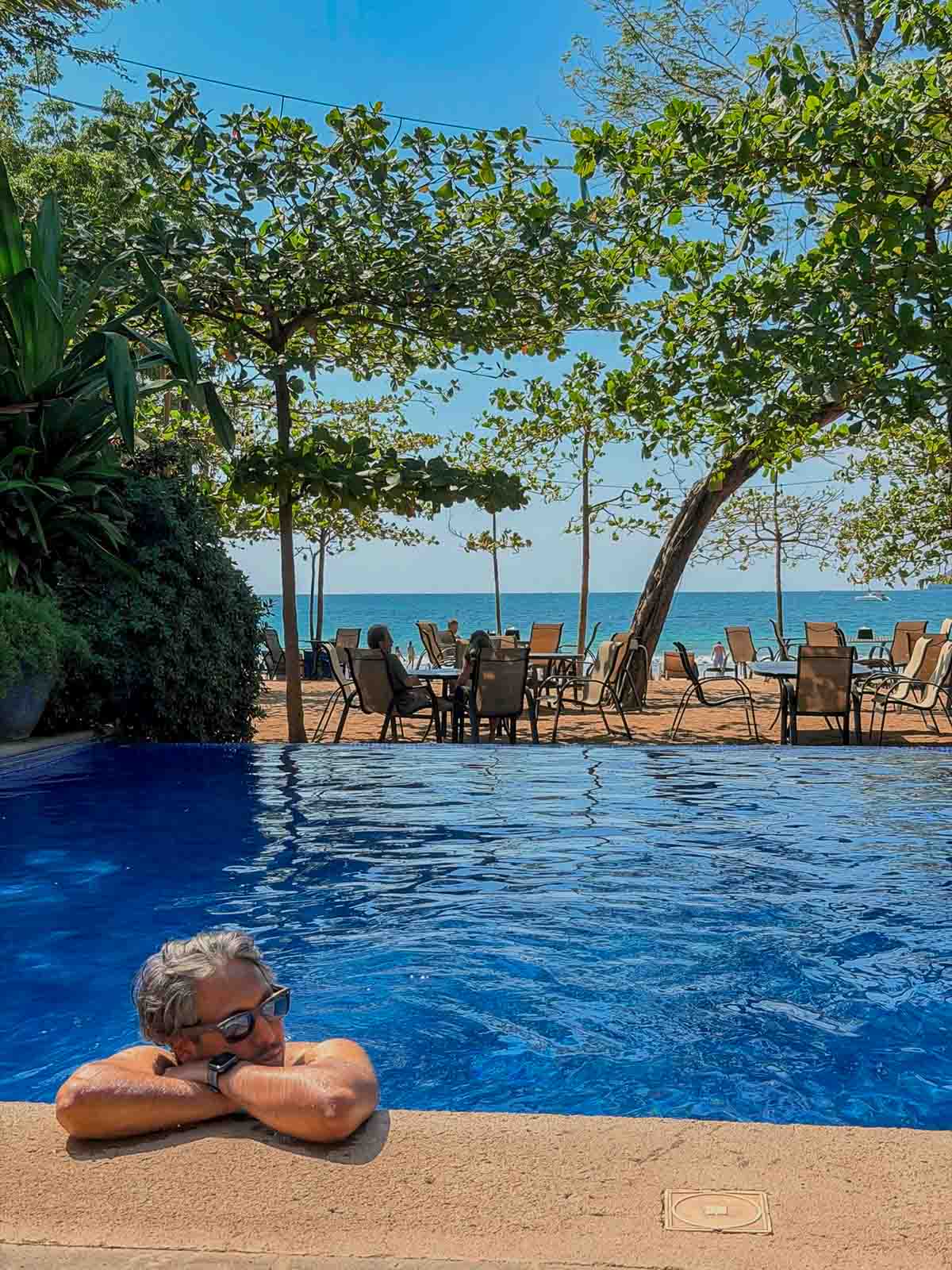 Riz relaxing in a blue pool. Behind him is Playa Langosta.