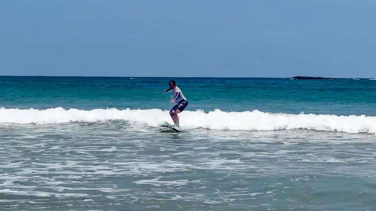 Riz learning to surf in the blue water at Playa Tamarindo.