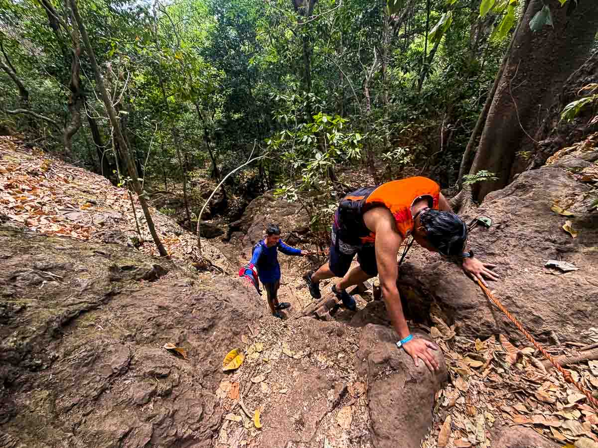 Riz climbs down the side of a small rock while hiking in Curubande, Costa Rica.
