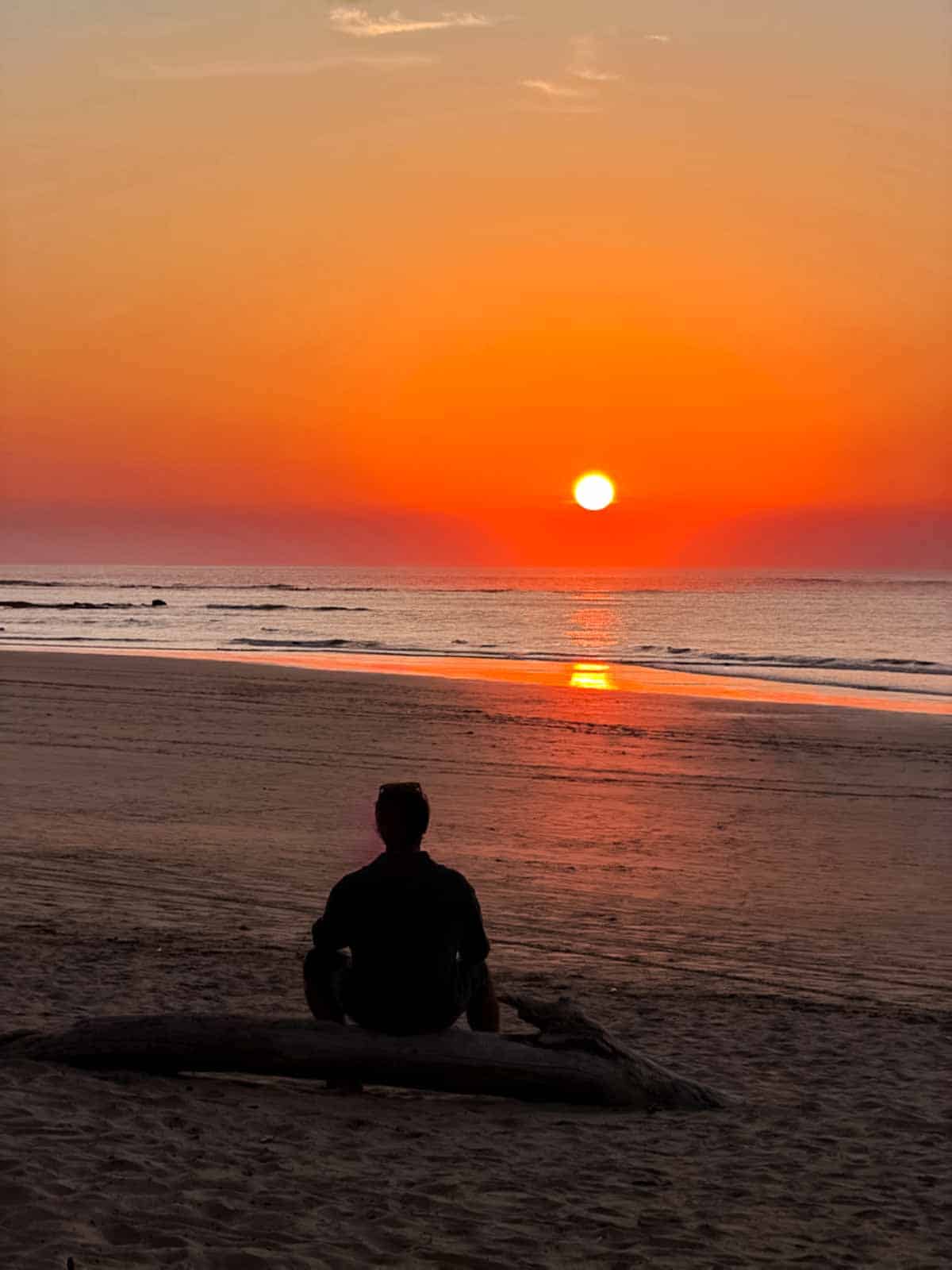 Riz sitting on a log watching the sunset on Tamarindo Beach.