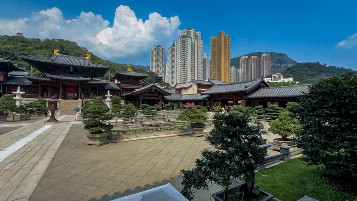 Traditional halls and carefully pruned trees in Chi Lin Nunnery's courtyard, with high-rise buildings behind.