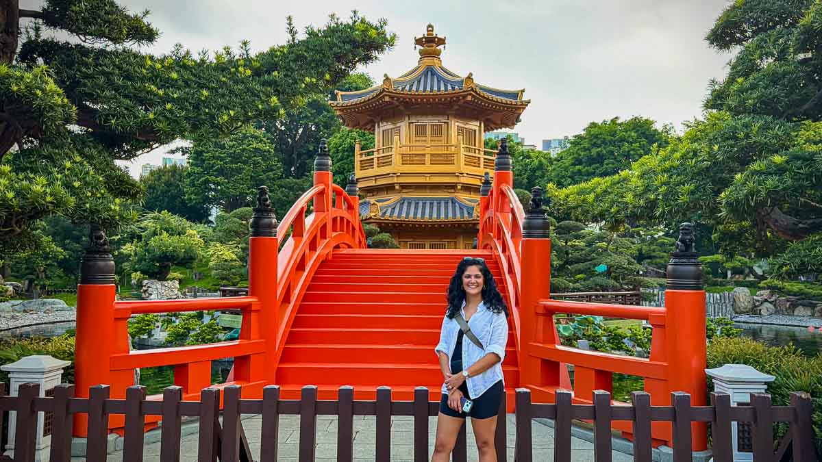 Reem standing beside the red-orange bridge leading to Nan Lian Garden’s golden pavilion.