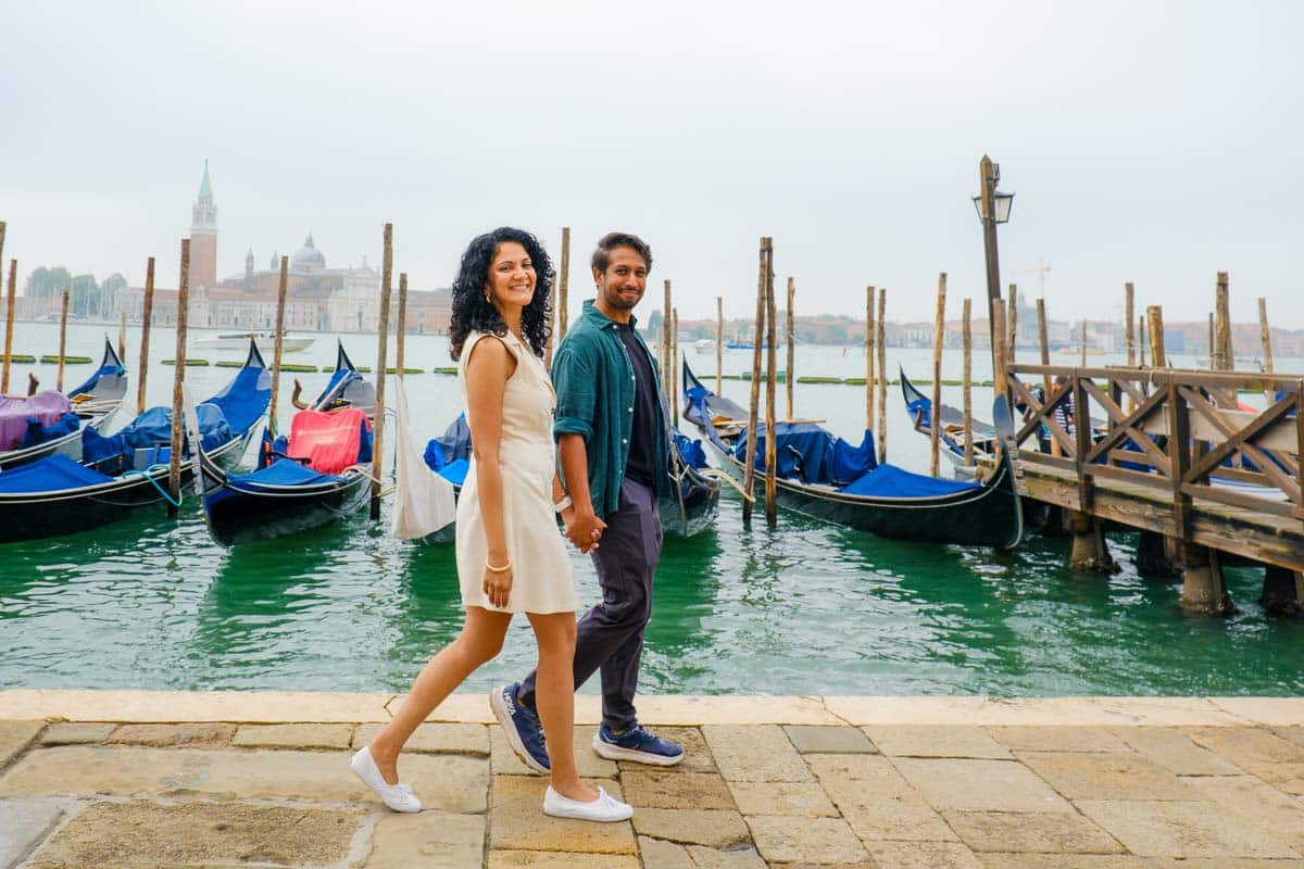 Riz and Reem walking beside gondolas on the Venice waterfront.