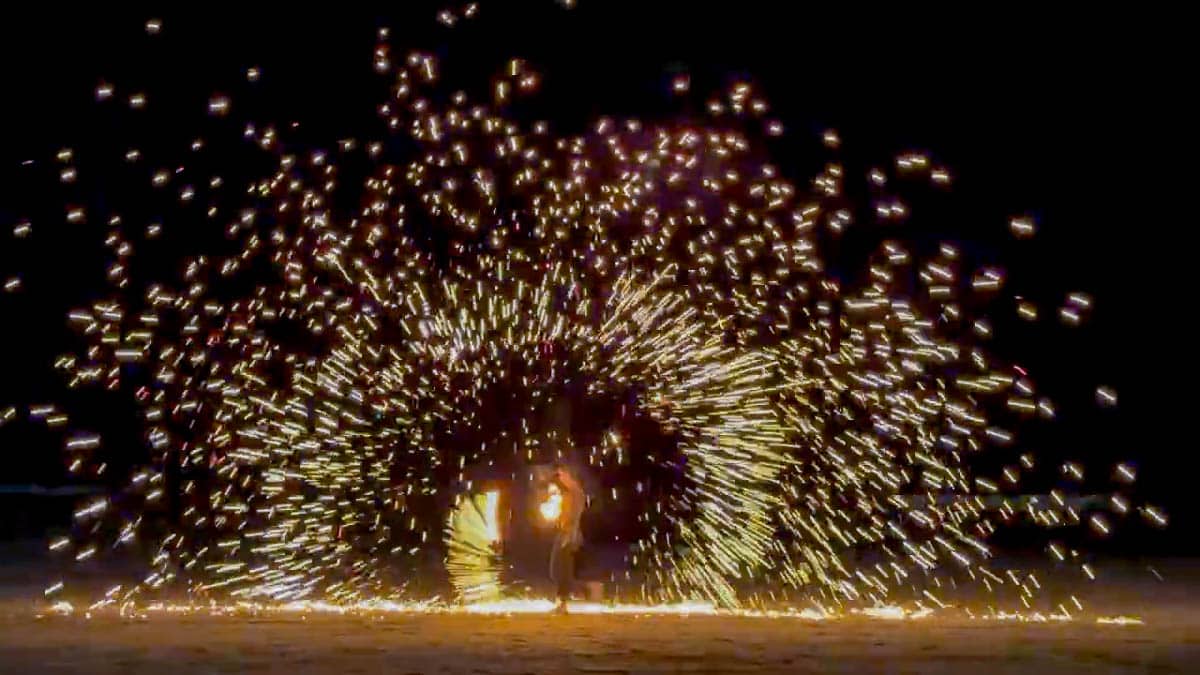 Fire performer creating a dramatic shower of sparks during an evening show at Namu Restaurant