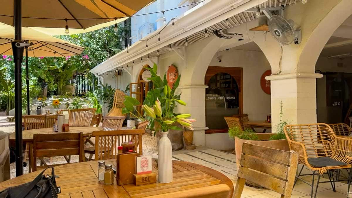 Outdoor dining area at Sol Bakery Tamarindo with wooden tables, umbrellas, and white archways